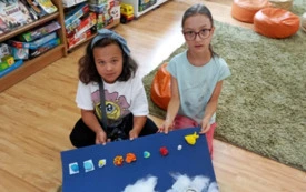 Dwie dziewczynki prezentują wykonaną przez siebie makietę kosmosu 3D